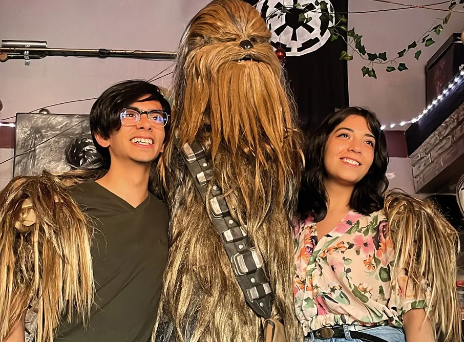 Dos amigos posan abrazados con Chewbacca