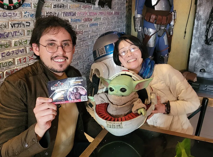 Pareja con Grogu y R2-D2 muestra una tarjeta del café