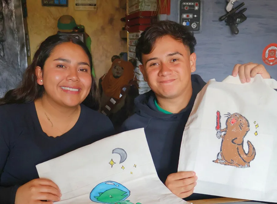 Dos asistentes muestran las bolsas de tela que dibujaron
