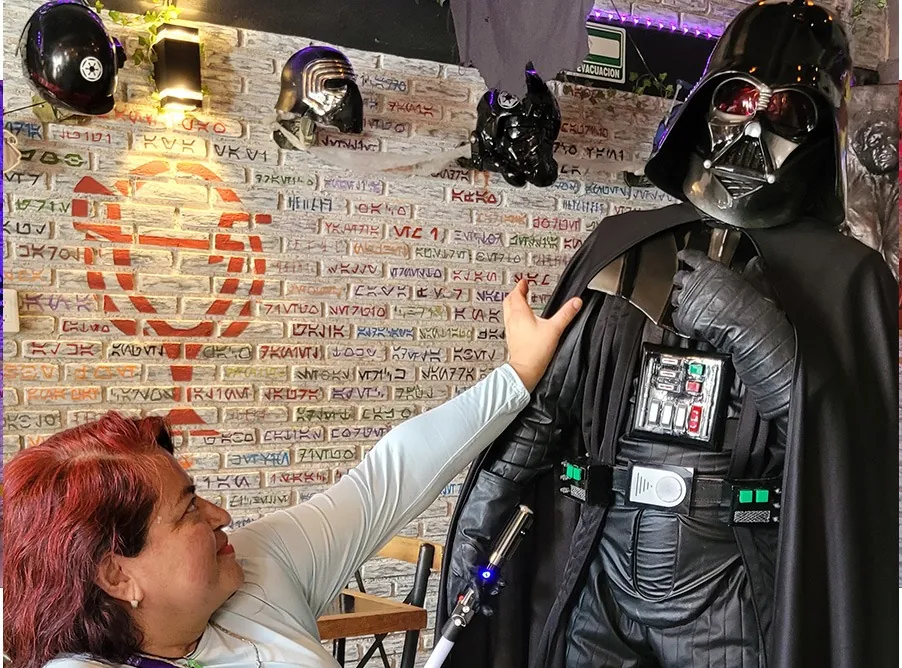 Una visitante saluda a Darth Vader frente al muro de ladrillo